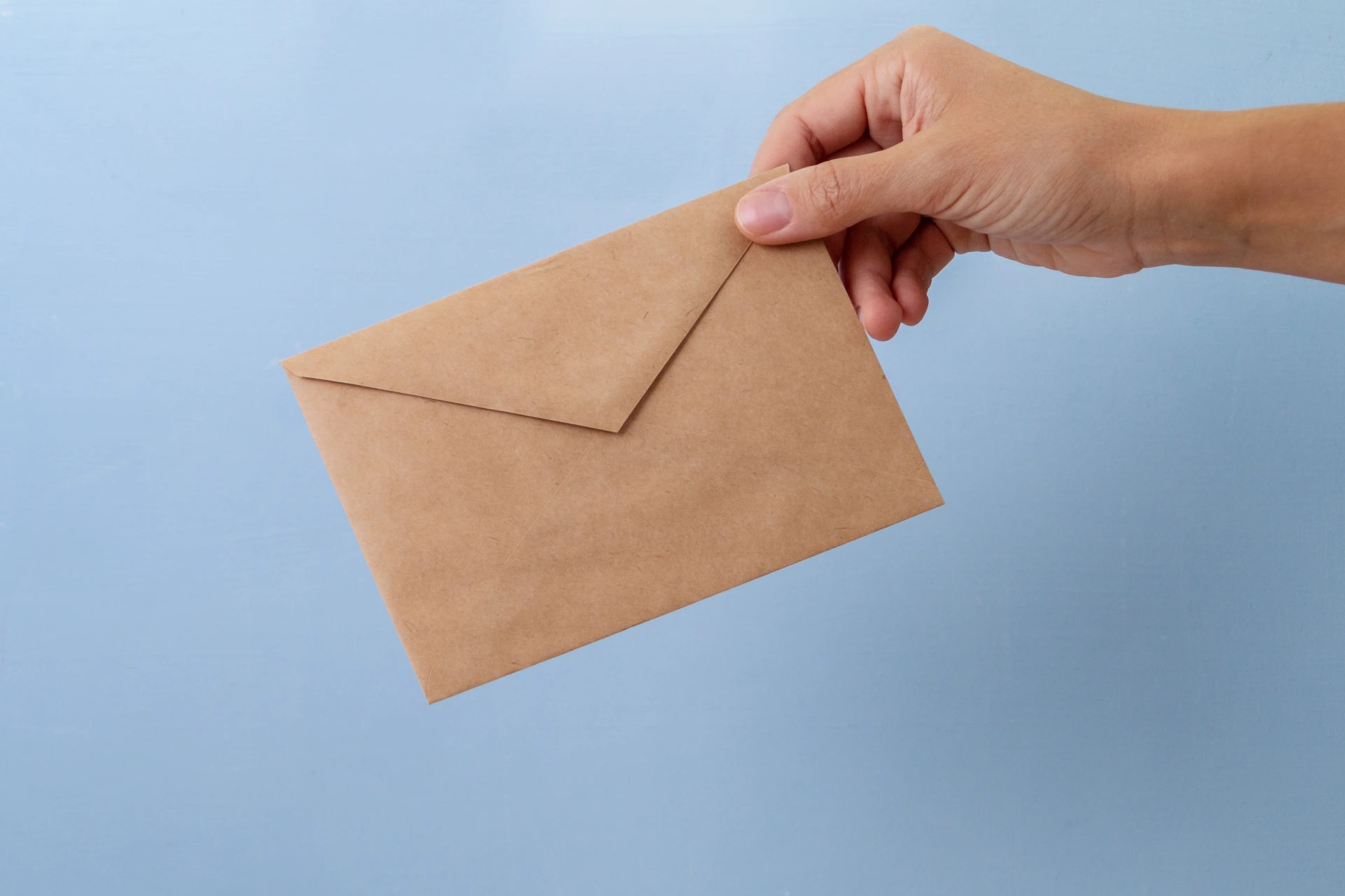 hand holding brown envelope on blue background