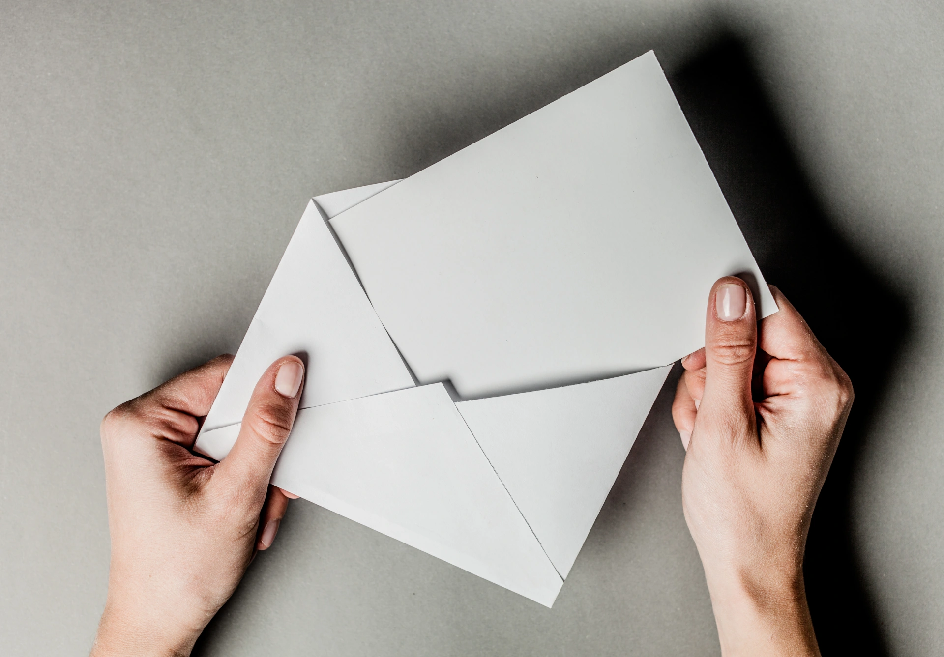 hand holds envelope with card on grey background