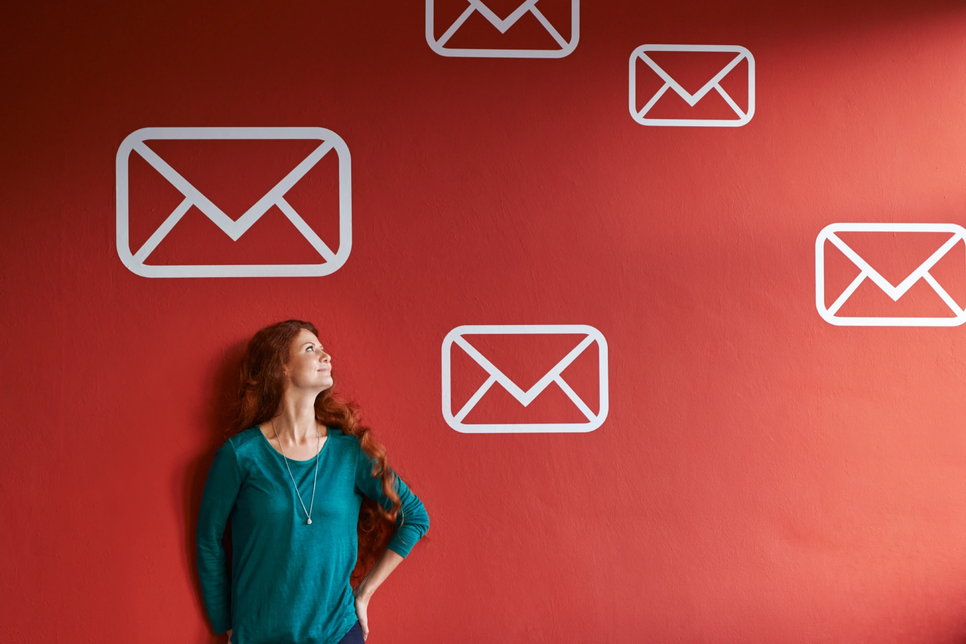 woman looking at email symbols on red wall